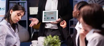 Consultants reviewing a dashboard on a tablet in a meeting