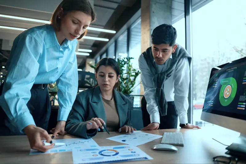 Three engineers reviewing a financial dashboard together at a desk