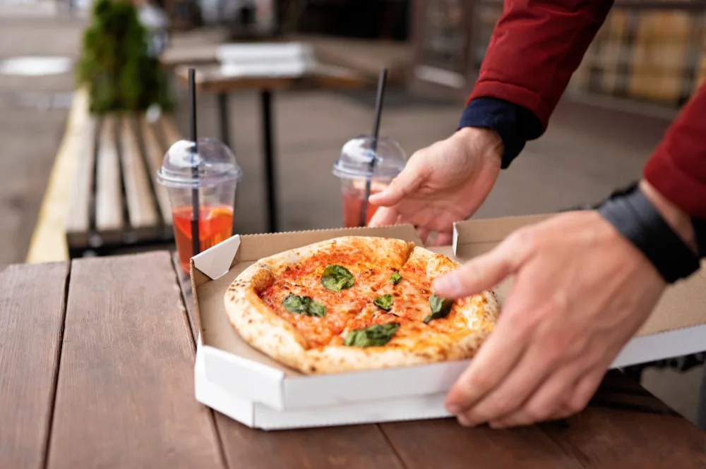Hands opening a pizza delivery box