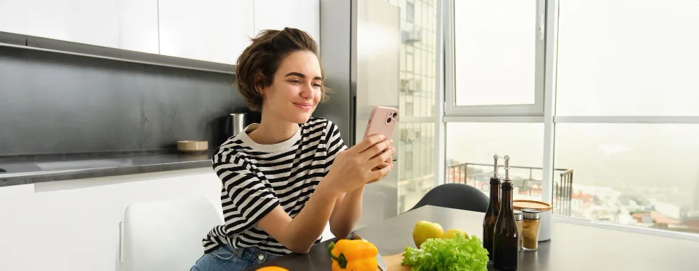 Woman ordering food on her phone in a kitchen