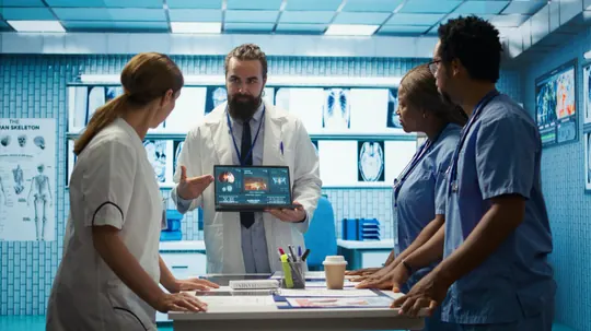 A doctor showing a tablet to three nurses in a hospital