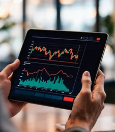 Hands holding a tablet showing a trading chart
